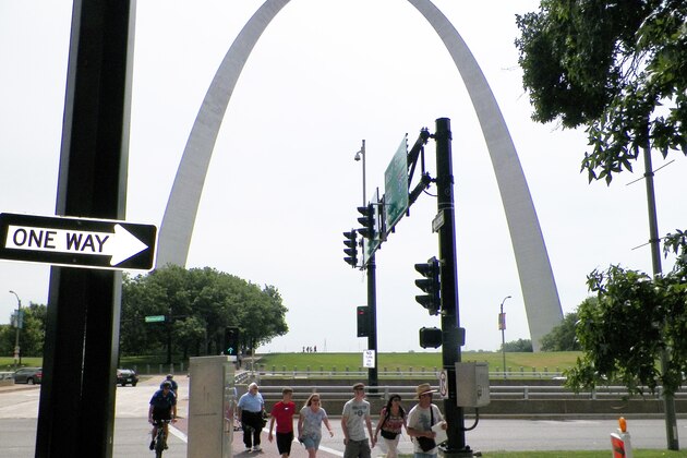 Pedestrians cross a street near the Gateway Arch Friday, Aug. 2, 2013, in St. Louis. The $380 million project to upgrade the grounds of the Gateway Arch officially began Friday as two members of President Barack Obama's Cabinet helped break ground. (AP Photo/Jim Salter)