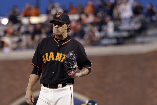 San Francisco Giants starting pitcher Jake Peavy stands on the mound as Oakland Athletics' Marcus Semien, rear, rounds the bases on a solo home run during the second inning of an exhibition baseball game Thursday, April 2, 2015, in San Francisco. (AP Photo/Marcio Jose Sanchez)