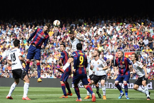 FC Barcelona's Gerard Pique, second left, duels for the ball against Valencia during a Spanish La Liga soccer match at the Camp Nou stadium in Barcelona, Spain, Saturday, April 18, 2015. (AP Photo/Manu Fernandez)