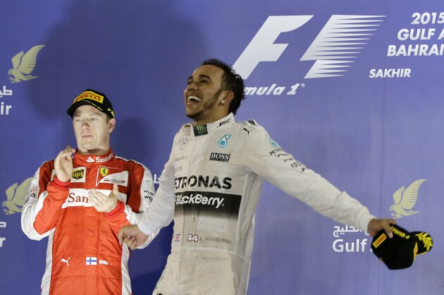 Mercedes driver Lewis Hamilton of Britain celebrates on the podium after winning the Bahrain Formula One Grand Prix as third placed Ferrari driver Kimi Raikkonen of Finland clapping as they stand on the podium after at the Formula One Bahrain International Circuit in Sakhir, Bahrain, Sunday, April 19, 2015. (AP Photo/Hassan Ammar)