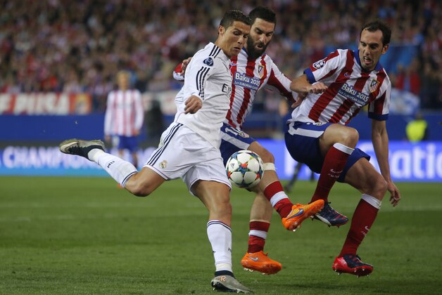 Real Madrid's Cristiano Ronaldo fights for the ball against Atletico's Diego Godin and Atletico's Arda Turan during the Champions League quarterfinal first leg soccer match between Atletico Madrid and Real Madrid at the Vicente Calderon stadium in Madrid, Spain, Tuesday, April 14, 2015. (AP Photo/Andres Kudacki)