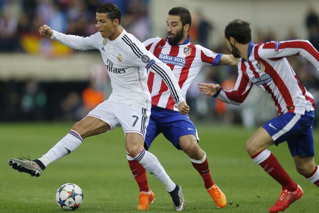 Atletico's Arda Turan, center, and Atletico's Juan Fran, right, try to stop Real Madrid's Cristiano Ronaldo, left, during the Champions League quarterfinal, first leg soccer match between Atletico de Madrid and Real Madrid at the Vicente Calderon stadium in Madrid, Spain, Tuesday, April 14, 2015. (AP Photo/Daniel Ochoa de Olza)
