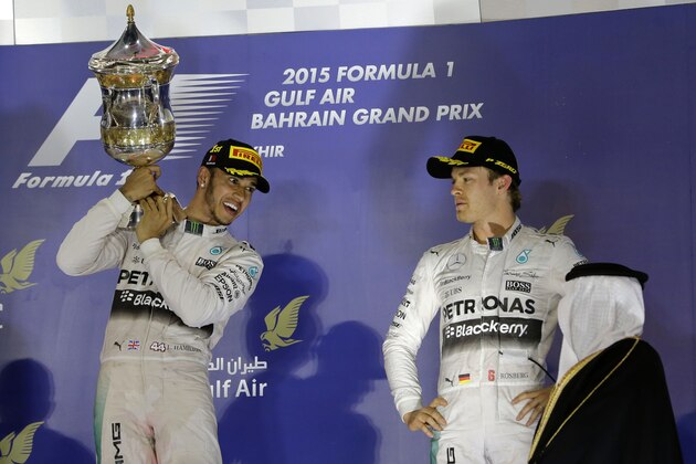 Mercedes driver Lewis Hamilton of Britain, winner, left, holds up his trophy after winning the Bahrain Formula One Grand Prix as third placed Mercedes driver Nico Rosberg of Germany, right, looks on while they stand on the podium after the Formula One Bahrain International Circuit in Sakhir, Bahrain, Sunday, April 19, 2015. (AP Photo/Hassan Ammar)