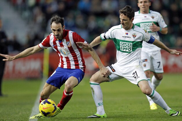 Atletico Madrid's Juanfran, left, duels for the ball with Elche's Jose Eduardo Albacar Gallego, right,  during their La Liga soccer match at the Manuel Martinez Valero stadium in Elche, Spain, Saturday, Nov. 30, 2013. (AP Photo/Alberto Saiz)