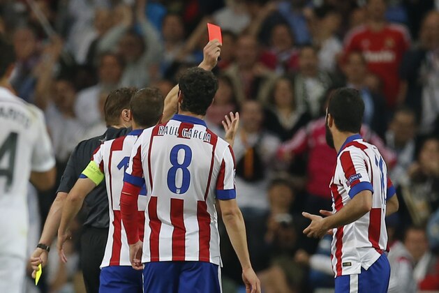 Referee Felix Brych of Germany shows the red card to Atletico's Arda Turan, right, during the second leg quarterfinal Champions League soccer match between Real Madrid and Atletico Madrid at Santiago Bernabeu stadium in Madrid, Spain, Wednesday April 22, 2015. (AP Photo/Paul White)