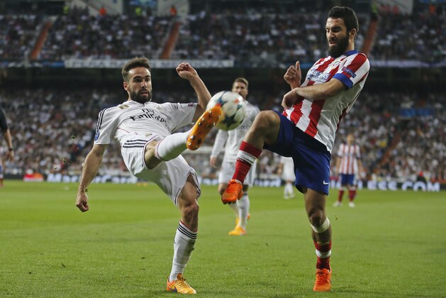 Real Madrid's Daniel Carvajal, left, clears the ball before Atletico's Arda Turan during the second leg quarterfinal Champions League soccer match between Real Madrid and Atletico Madrid at Santiago Bernabeu stadium in Madrid, Spain, Wednesday April 22, 2015. (AP Photo/Paul White)