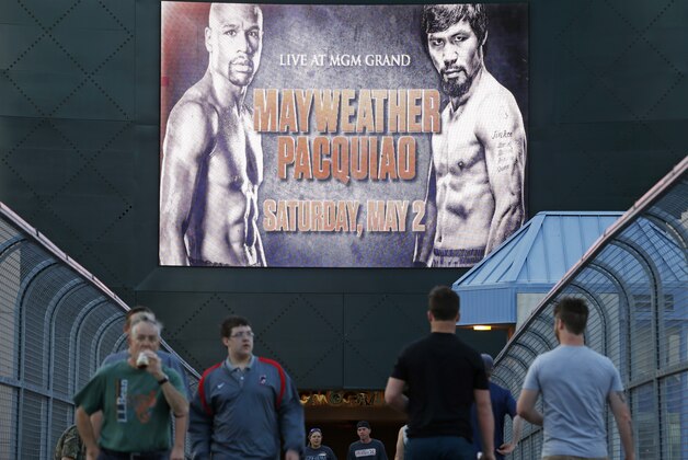 People walk across a footbridge by a sign advertising the boxing bout between Floyd Mayweather Jr. and Manny Pacquiao, Wednesday, April 22, 2015, in Las Vegas. (AP Photo/John Locher)
