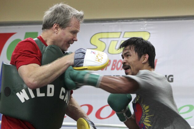 FILE - In this March 23, 2011, file photo, boxer Manny Pacquiao, right, connects to the chest of trainer Freddie Roach during a workout at the resort city of Baguio, in northern Philippines. Roach has guided Pacquiao to the pinnacle of boxing, yet the most celebrated trainer of his era still rises before dawn and wins his daily fight with Parkinson's disease because he always finds new reasons to live.  (AP Photo/Bullit Marquez, File)