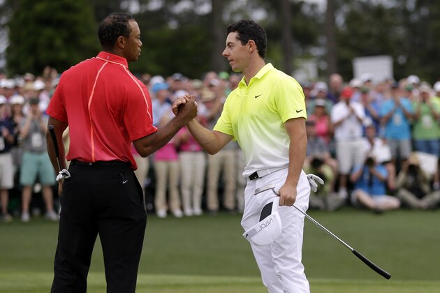 Tiger Woods, left, shakes hands with Rory McIlroy, of Northern Ireland, on the 18th hole during the fourth round of the Masters golf tournament Sunday, April 12, 2015, in Augusta, Ga. (AP Photo/David J. Phillip)