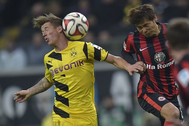 Dortmund's Erik Durm, left, and Frankfurt's Takashi Inui challenge for the ball during the German Bundesliga soccer match between Eintracht Frankfurt and Borussia Dortmund in Frankfurt,  Germany, Sunday, Nov. 30, 2014. Borussia Dortmund's Bundesliga troubles continued Sunday with a 2-0 loss at Eintracht Frankfurt that left the 2011 and 2012 champion bottom of the table after 13 games. (AP Photo/Martin Meissner)