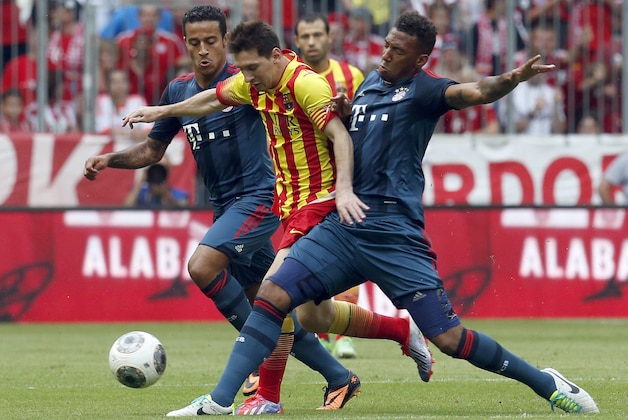 Barcelona's Messi, center, Munich's Thiago, left, and Munich's Jerome Boateng challenge for the ball during their friendly soccer match in the Allianz Arena stadium in Munich, southern Germany, on Wednesday, July 24, 2013. (AP Photo/Matthias Schrader)