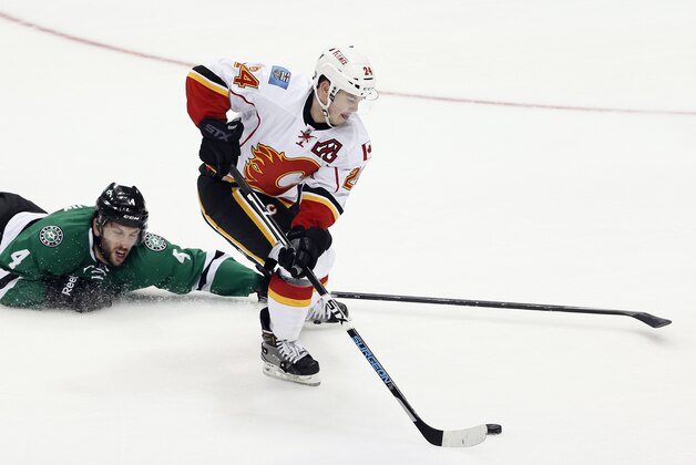 Calgary Flames' Jiri Hudler (24) of the Czech Republic handles the puck under pressure from Dallas Stars' Jason Demers (4) in the third period of an NHL hockey game Monday, March 30, 2015, in Dallas. The Flames won 5-3. (AP Photo/Tony Gutierrez)