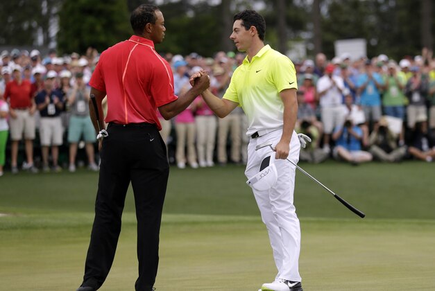 Tiger Woods, left, shakes hands with Rory McIlroy, of Northern Ireland, on the 18th hole during the fourth round of the Masters golf tournament Sunday, April 12, 2015, in Augusta, Ga. (AP Photo/David J. Phillip)