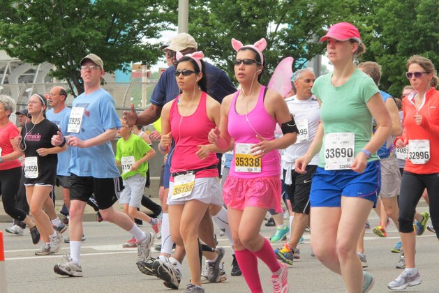 Two women wearing pig ears join thousands running and walking in a 5K on Saturday, May 4, 2013 in front of the Cincinnati Bengals stadium as part of weekend-long events of the Flying Pig Marathon, now in its 15th year. A 5K and 10K on Saturday were sold-out, as were a half and full marathon set for Sunday, with more than 33,000 participants expected overall. (AP Photo/Amanda Lee Myers)