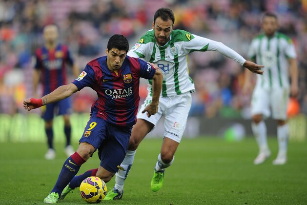 FC Barcelona's Luis Suarez, from Uruguay, left, duels for the ball against Cordoba's Deivid Rodríguez during a Spanish La Liga soccer match at the Camp Nou stadium in Barcelona, Spain, Saturday, Dec. 20, 2014. (AP Photo/Manu Fernandez)