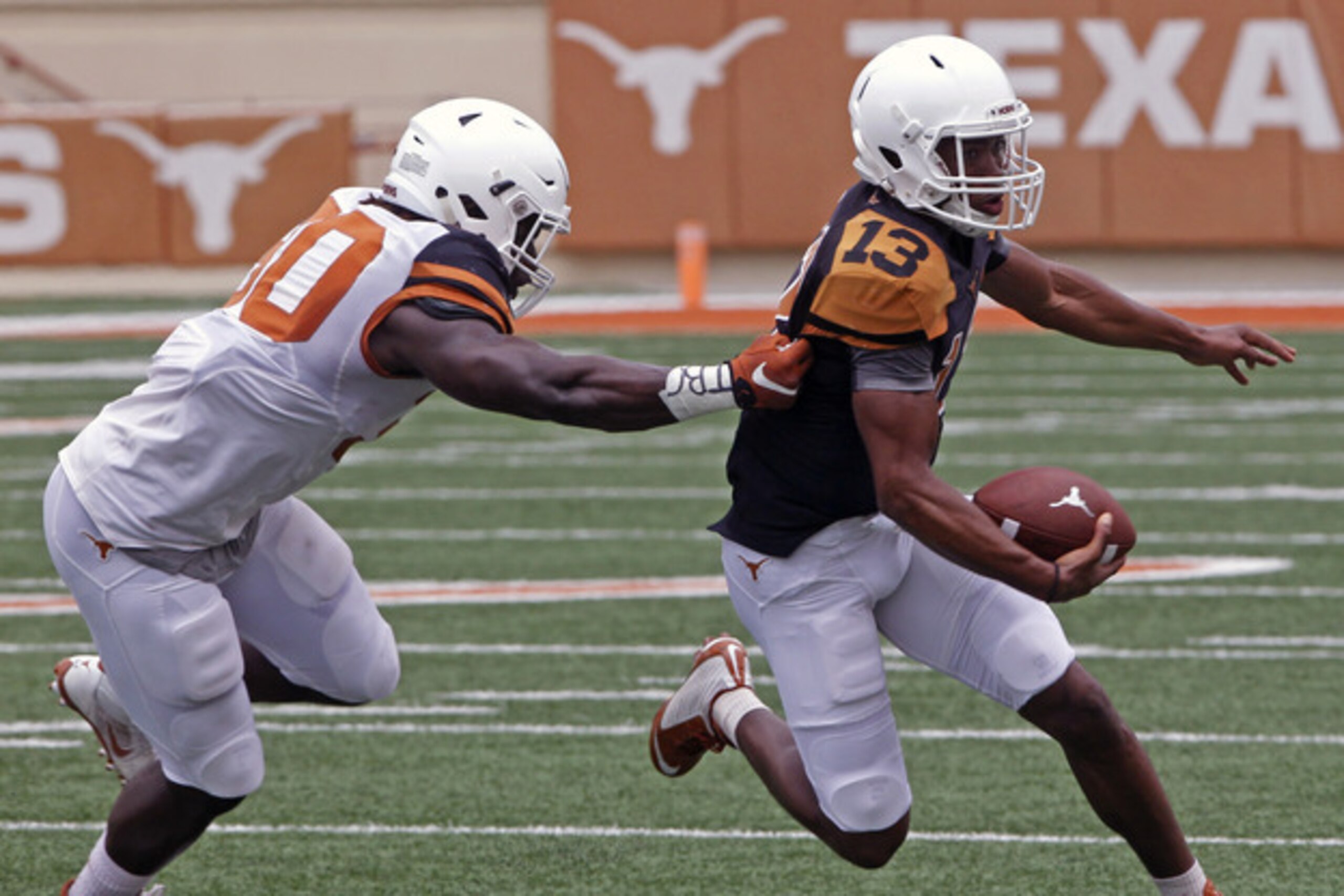 Texas quarterback Jerrod Heard, right, runs against linebacker Timothy Cole, left, during the first quarter of Texas' Orange and White spring NCAA college football game, Saturday, April 18, 2015, in Austin, Texas. (AP Photo/Michael Thomas)