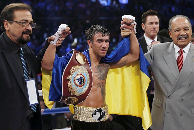 FILE - In this Sunday, Nov. 23, 2014 file photo, Vasyl Lomachenko of Ukraine celebrates after defeating Chonlatarn Piriyapinyo of Thailand during their WBO world featherweight boxing title match at the Venetian Macao in Macau. Vasyl Lomachenko is a ferocious puncher and a two-time Olympic gold medalist who won a world title belt in his third professional fight. He still isn't well known outside his native Ukraine, but the 27-year-old featherweight plans to change that when he takes a featured spot on the biggest pay-per-view show in recent boxing history. (AP Photo/Kin Cheung, File)