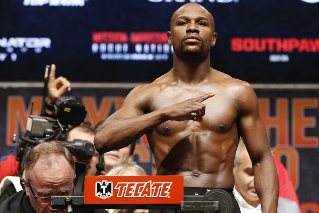 Floyd Mayweather Jr. poses during his weigh-in on Friday, May 1, 2015 in Las Vegas. The world weltherweight title fight between Mayweather Jr. and Manny Pacquiao is scheduled for May 2. At lower left is Nevada State Athletic Commission Executive Director Robert Bennett. (AP Photo/John Locher)
