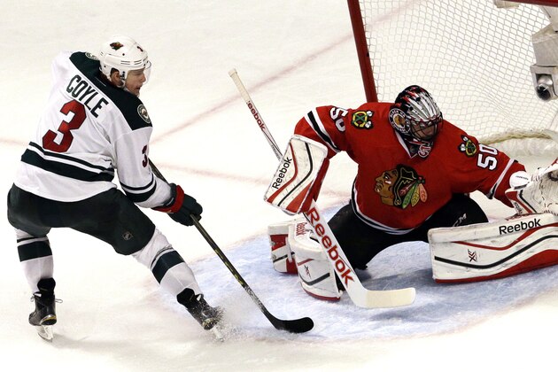 Chicago Blackhawks goalie Corey Crawford, right, blocks a shot by Minnesota Wild center Charlie Coyle, left, during the third period  of Game 1 in the second round of the NHL Stanley Cup hockey playoffs in Chicago, Friday, May 1, 2015. The Blackhawks won 4-3. (AP Photo/Nam Y. Huh)