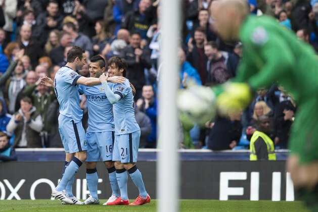 Manchester City's Sergio Aguero, second left, celebrates with teammates David Silva and Frank Lampard, left, after scoring from a mistake by Aston Villa's goalkeeper Brad Guzan, right, during the English Premier League soccer match between Manchester City and Aston Villa at the Etihad Stadium, Manchester, England, Saturday April 25, 2015. (AP Photo/Jon Super)