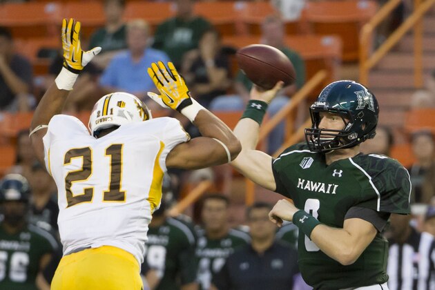 Wyoming linebacker Mark Nzeocha (21) rushes Hawaii quarterback Taylor Graham (8) in the first quarter of an NCAA college football game,  Saturday, Oct. 11, 2014, in Honolulu. (AP Photo/Eugene Tanner)