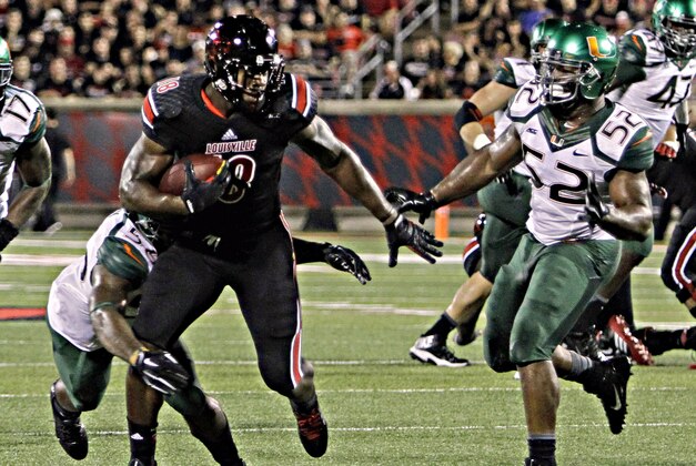 Louisville tight end Gerald Christian (18) runs by Miami linebacker Denzel Perryman (52) and Miami's Darrion Owens during the second half of an NCAA college football game in Louisville, Ky., Monday, Sept. 1, 2014. Louisville won 31-13. (AP Photo/Garry Jones)