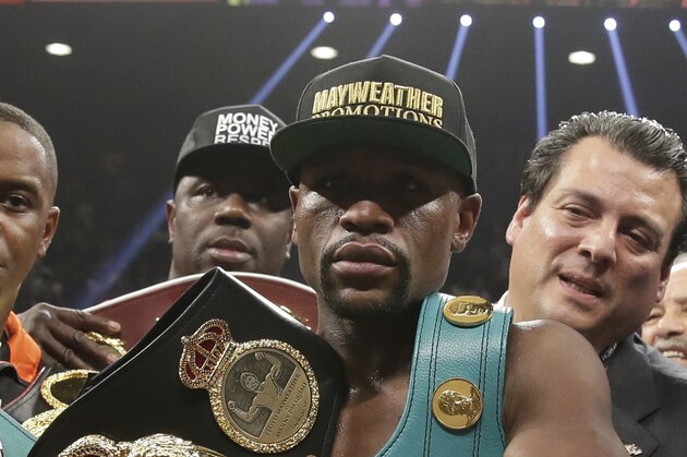 Floyd Mayweather Jr. carries the winner's belts after he defeated Manny Pacquiao, from the Philippines, in their welterweight title fight on Saturday, May 2, 2015 in Las Vegas. (AP Photo/Isaac Brekken)