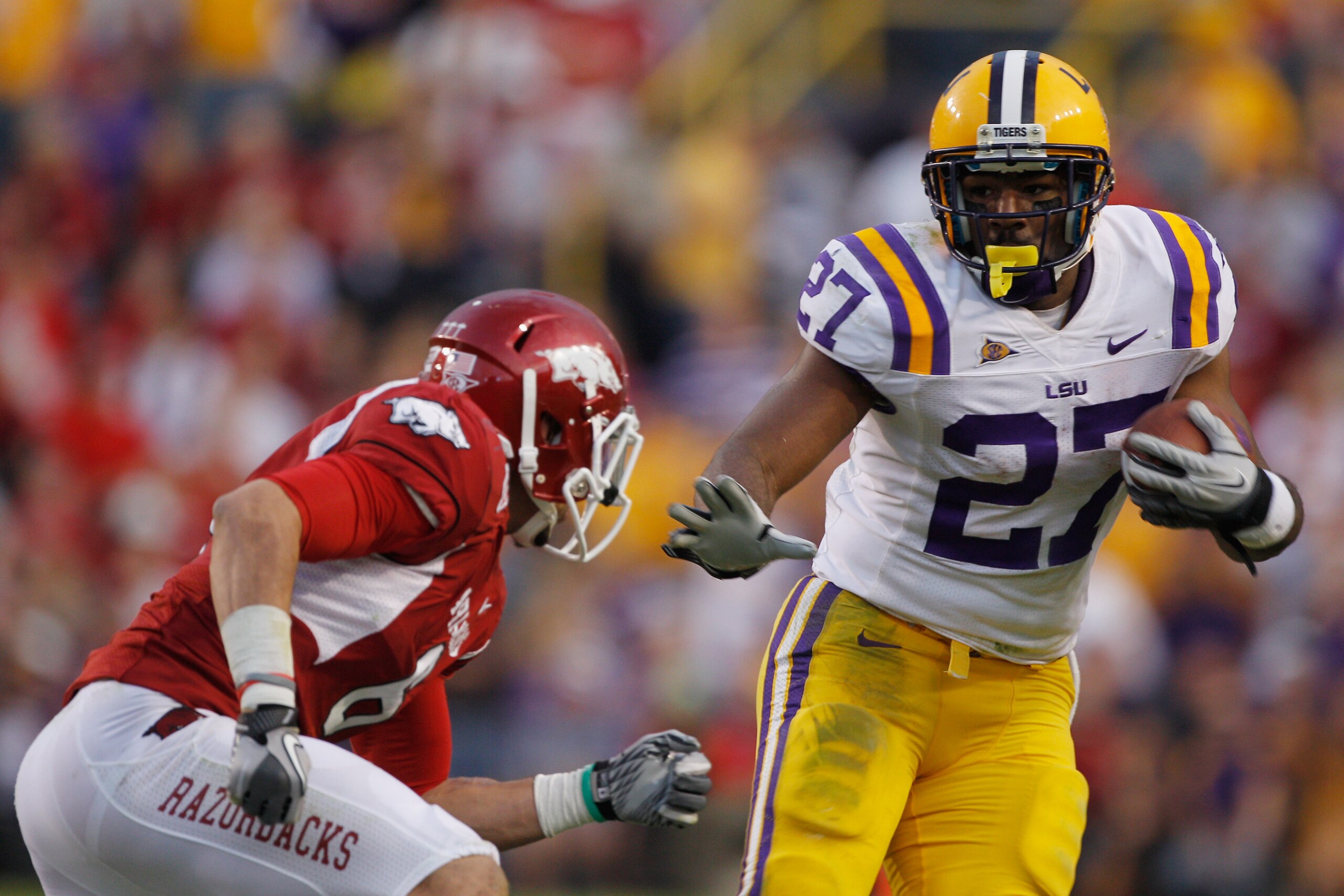 BATON ROUGE, LA - NOVEMBER 25: Kenny Hilliard #27 of the Louisiana State University Tigers tries to avoid a tackle by Isaac Madison #6 of the Arkansas Razorbacks at Tiger Stadium on November 25, 2011 in Baton Rouge, Louisiana. The Tigers defeated the Razorbacks 41-17. (Photo by Chris Graythen/Getty Images) BATON ROUGE, LA - NOVEMBER 25: Kenny Hilliard #27 of the Louisiana State University Tigers tries to avoid a tackle by Isaac Madison #6 of the Arkansas Razorbacks at Tiger Stadium on November 25, 2011 in Baton Rouge, Louisiana. The Tigers defeated the Razorbacks 41-17. (Photo by Chris Graythen/Getty Images)
