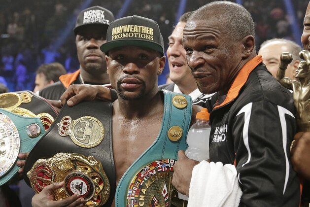 Floyd Mayweather Jr., left, poses with his champion's belts and his father, head trainer Floyd Mayweather Sr., after his victory over Manny Pacquiao, from the Philippines,  in their welterweight title fight on Saturday, May 2, 2015 in Las Vegas. (AP Photo/Isaac Brekken)