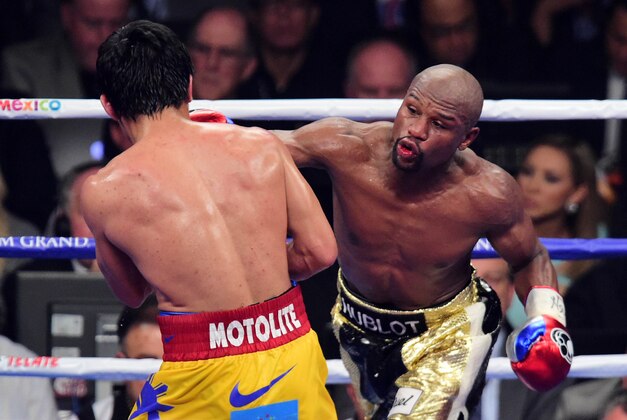 May 2, 2015; Las Vegas, NV, USA; Floyd Mayweather (black/gold trunks) and Manny Pacquiao (yellow/red trunks) box during their world welterweight championship bout at MGM Grand Garden Arena. Mayweather won via unanimous decision. Mandatory Credit: Joe Camporeale-USA TODAY Sports