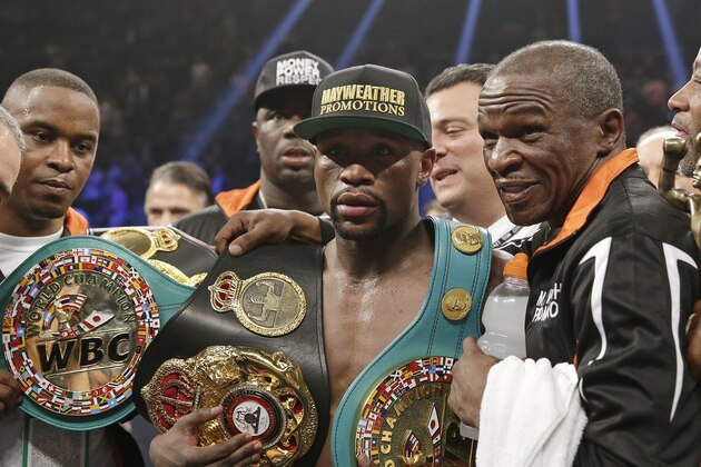 Floyd Mayweather Jr., left, poses with his champion's belts and his father, head trainer Floyd Mayweather Sr., after his victory over Manny Pacquiao, from the Philippines,  in their welterweight title fight on Saturday, May 2, 2015 in Las Vegas. (AP Photo/Isaac Brekken)