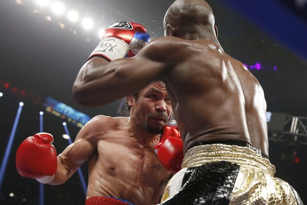 Manny Pacquiao, left, from the Philippines, trades blows with Floyd Mayweather Jr., during their welterweight title fight on Saturday, May 2, 2015 in Las Vegas. (AP Photo/John Locher)