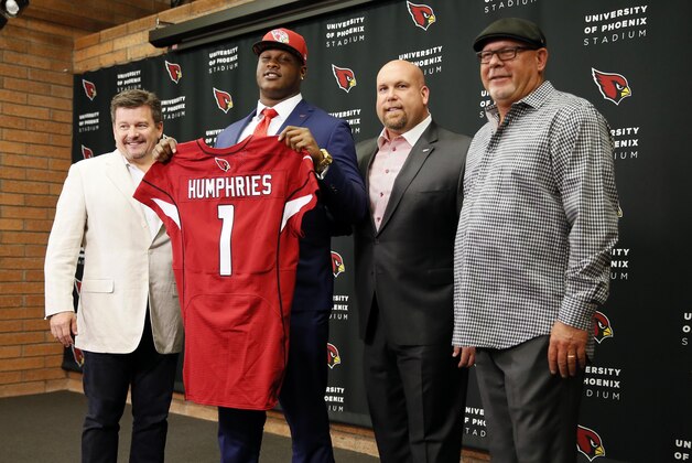 Arizona Cardinals' first-round draft pick D.J. Humphries holds his jersey for a photograph with Cardinals president Michael Bidwill, left, general manager Steve Keim, second from right, and head coach Bruce Arians, right, after speaking to the media at an NFL football news conference, Friday, May 1, 2015, in Tempe, Ariz. Humphries, a tackle from Florida, was selected 24th overall Thursday night at the NFL draft. (AP Photo/Matt York)
