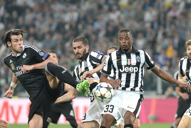 Real Madrid Gareth Bale, left, challenges for the ball with Juventus' Patrice Evra during the Champions League, semifinal soccer match between Juventus and Real Madrid at the Juventus Stadium in Turin, Italy, Tuesday, May 5, 2015. (AP Photo/Massimo Pinca)