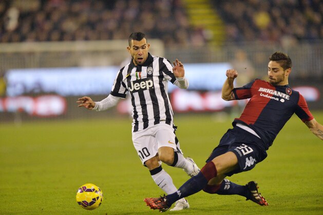 CAGLIARI, ITALY - DECEMBER 18:  Carlos Tevez #10 of Juventus FC and Marco Capuano of Cagliari in action during the Serie A match at Stadio Sant'Elia on December 18, 2014 in Cagliari, Italy.  (Photo by Enrico Locci/Getty Images)