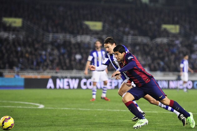 Barcelona's Luis Suarez of Uruguay, right, duels for the ball with Yuri Berchiche during their La Liga soccer match between Real Sociedad and Barcelona, at Anoeta stadium in San Sebastian, northern Spain, Sunday, Jan.4, 2015. Barcelona lost the match 1-0. (AP Photo/Alvaro Barrientos)