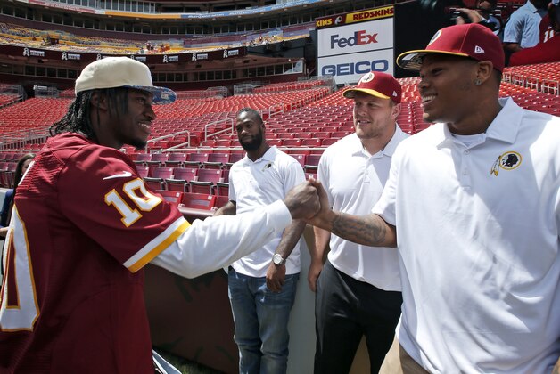 Washington Redskins  quarterback Robert Griffin III, left, greets draft picks, from right, linebacker Preston Smith, offensive lineman Brandon Scherff, and running back Matt Jones, during am NFL football draft day fan fest Saturday, May 2, 2015, in Landover, Md. (AP Photo/Alex Brandon)
