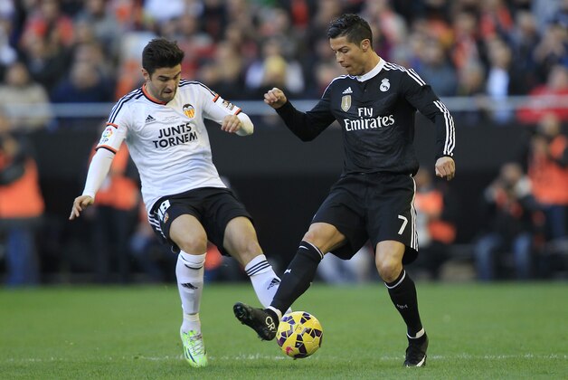 Real Madrid's Cristiano Ronaldo, right, duels for the ball with Valencia's Javi Fuego, left,  during a Spanish La Liga soccer match at the Mestalla stadium in Valencia, Spain, on Sunday, Jan. 4, 2015.(AP Photo/Alberto Saiz)