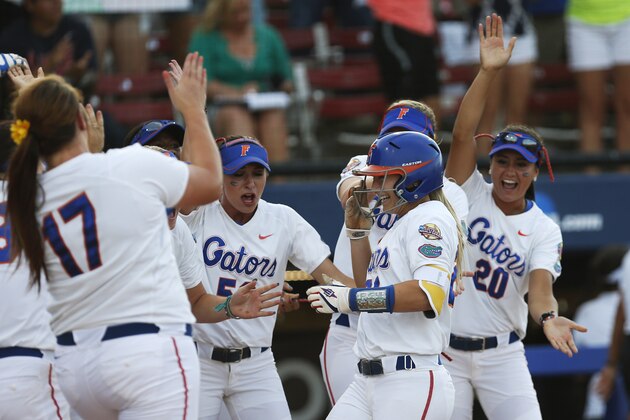 Florida's Kirsti Merritt, center, is greeted by her teammates at home plate following her home run in the second inning of an NCAA Women's College World Series softball tournament game against Alabama in Oklahoma City, Tuesday, June 3, 2014. (AP Photo/Sue Ogrocki)