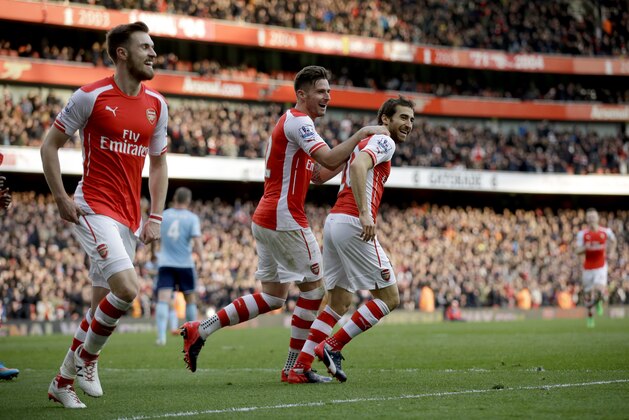 Arsenal's Mathieu Flamini, right, celebrates after scoring his side's third goal with Olivier Giroud, center, and Aaron Ramsey during the English Premier League soccer match between Arsenal and West Ham United at the Emirates Stadium in London, Saturday, March 14, 2015.  (AP Photo/Matt Dunham)