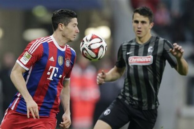 Bayern's Robert Lewandowski from Poland, left, and Freiburg's Marc-Oliver Kempf challenge for the ball during the German first division Bundesliga soccer match between FC Bayern and SC Freiburg in the Allianz Arena in Munich, Germany, on Tuesday, Dec. 16, 2014. (AP Photo/Matthias Schrader)