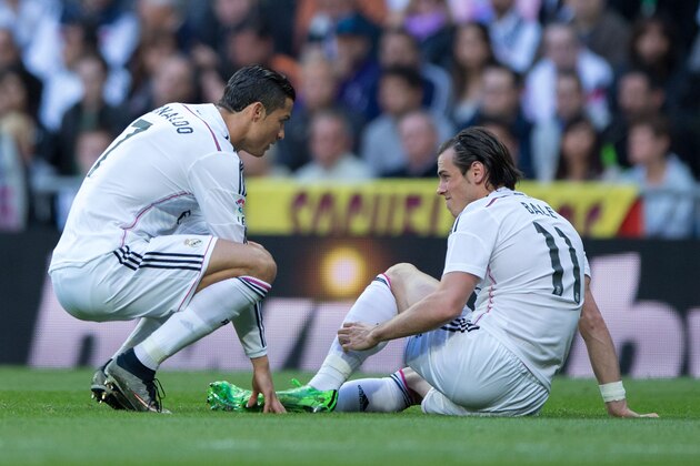 MADRID, SPAIN - APRIL 18: Gareth Bale (R) of Real Madrid CF touches his leg as his teammate Cristiano Ronaldo (L) assists him during the La Liga match between Real Madrid CF and Malaga CF at Estadio Santiago Bernabeu on April 18, 2015 in Madrid, Spain.  (Photo by Gonzalo Arroyo Moreno/Getty Images)