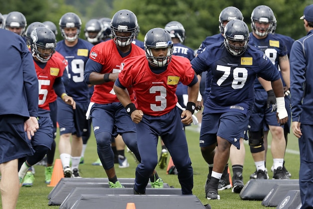 Seattle Seahawks quarterback Russell Wilson (3) leads players through a drill at an NFL organized team activity football practice Thursday, June 12, 2014, in Renton, Wash. (AP Photo/Elaine Thompson)