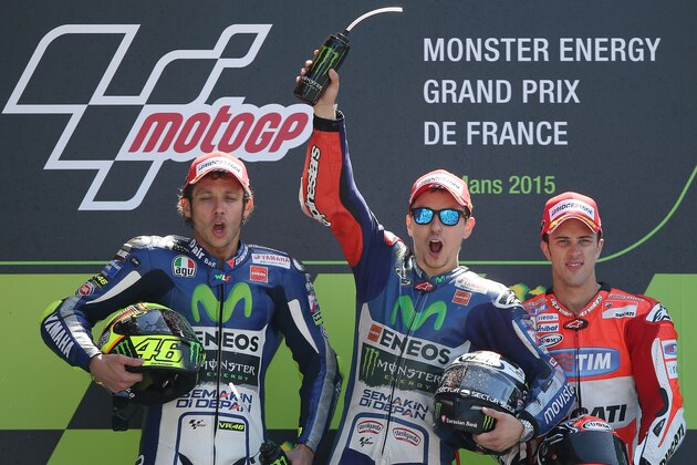 Spanish Moto GP rider Jorge Lorenzo, center, jubilates on the podium after winning the France Motorcycle Grand Prix race ahead of his teammate Italian Moto GP rider Valentino Rossi, left, and Italian Moto GP rider Andrea Dovizioso, right, at the Bugatti race track in Le Mans, western France, Sunday, May 17, 2015. (AP Photo/David Vincent)