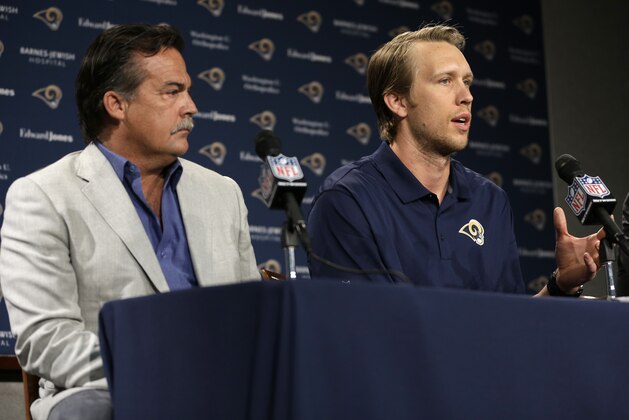 St. Louis Rams head coach Jeff Fisher, left, listens as Nick Foles is introduced as the NFL football team's new quarterback during a news conference Friday, March 13, 2015, in St. Louis. Foles was traded to the Rams earlier this week, with Sam Bradford going to the Philadelphia Eagles in a quarterback swap. (AP Photo/Jeff Roberson)