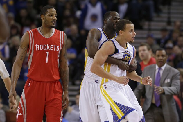 Golden State Warriors guard Stephen Curry (30) is held back by forward Draymond Green from going after Houston Rockets forward Trevor Ariza (1) during the second half of an NBA basketball game in Oakland, Calif., Wednesday, Jan. 21, 2015. (AP Photo/Jeff Chiu)