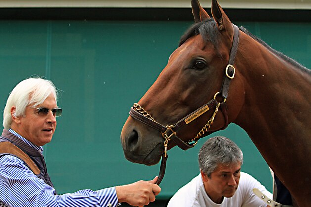 Trainer Bob Baffert, left, holds Preakness Stakes winner American Pharoah outside the stakes barn, Sunday, May 17, 2015 at Pimlico Race Course in Baltimore while groom Eduardo Garcia gives the Triple Crown hopeful a bath.  (AP Photo/Garry Jones)
