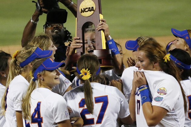 Florida pitcher Hannah Rogers holds the trophy as the team celebrates following an NCAA Women's College World Series softball tournament game against Alabama in Oklahoma City, Tuesday, June 3, 2014. Florida won the game 6-3 and took the title. (AP Photo/Sue Ogrocki)