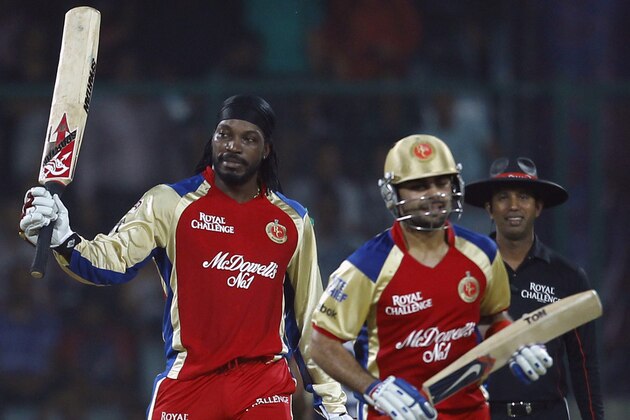 Chris Gayle of Royal Challengers Bangalore, left, raises his bat after scoring a century as teammate  Virat Kohli walks back after congratulating him during their IPL cricket match against Delhi Daredevils, in New Delhi, India, Thursday, May 17, 2012. (AP Photo/ Saurabh Das)