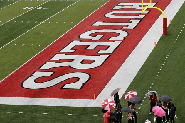 People stand together on the field in the rain at Rutgers football stadium before an NCAA college football game between Rutgers and Penn State, Saturday, Sept. 13, 2014, in Piscataway, N.J. (AP Photo/Mel Evans)
